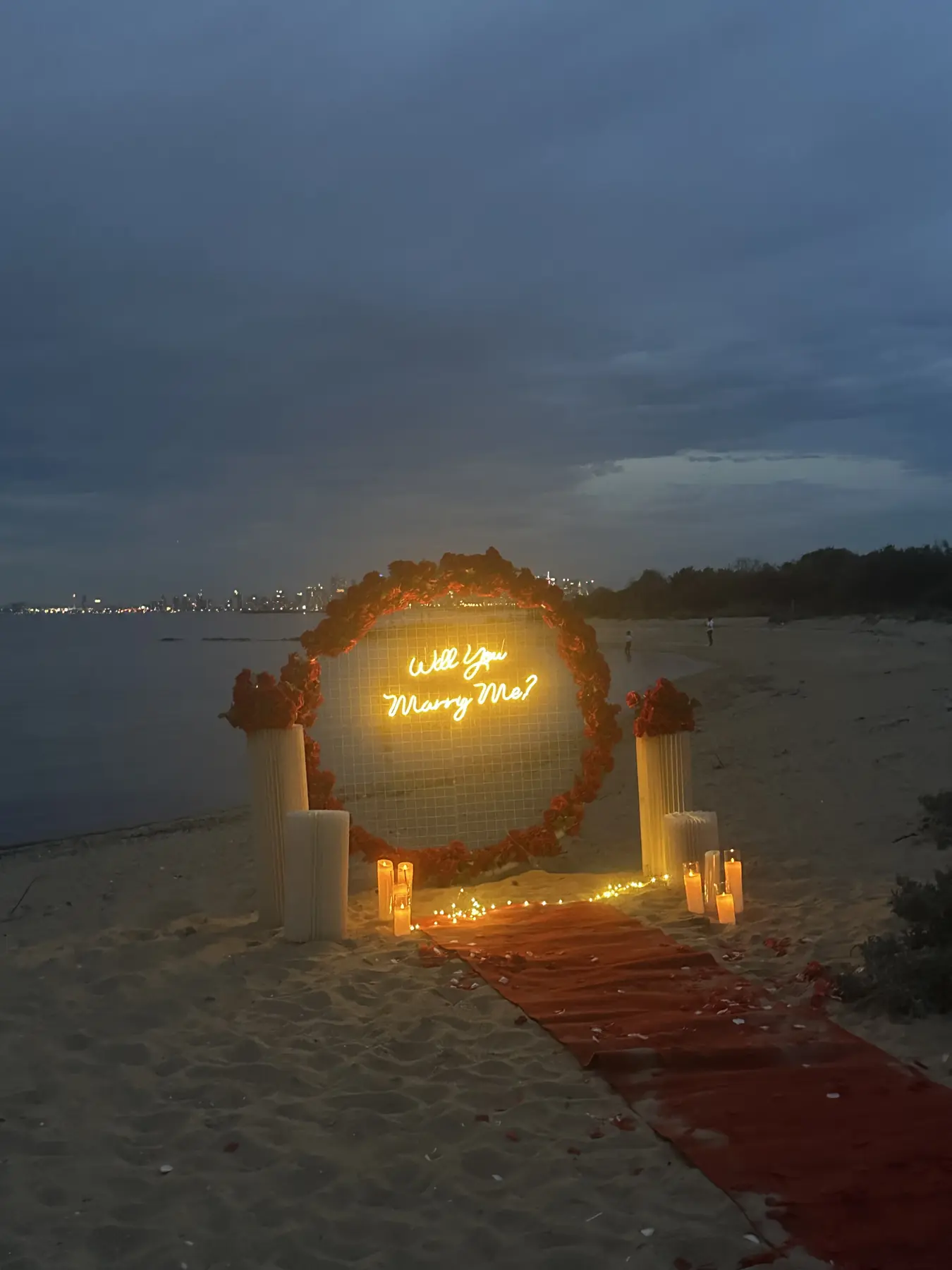 Proposal arch glowing with warm lights on a beach at dusk